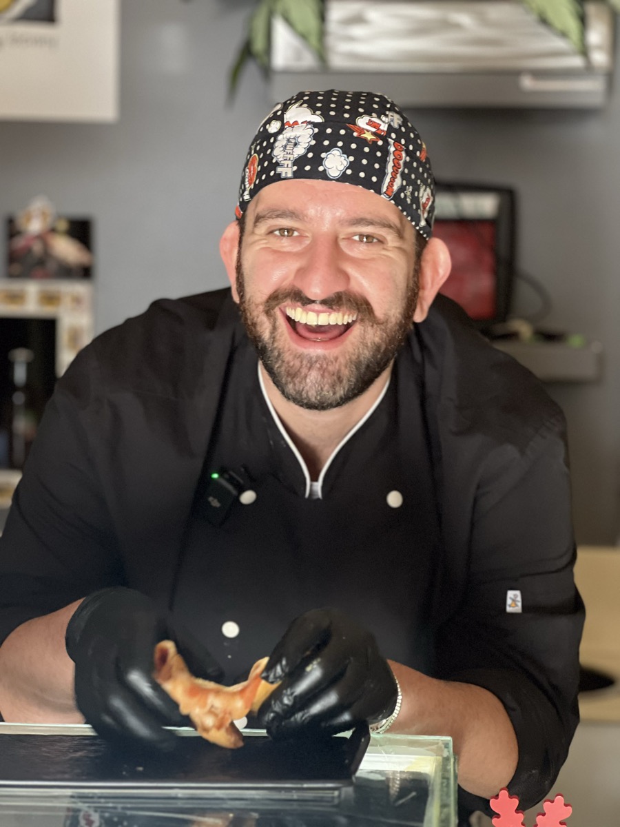 Benny, il panzerottaro di Panzeropoli, sorride con un panzerotto in mano nel suo locale di Piazza Mercantile a Bari